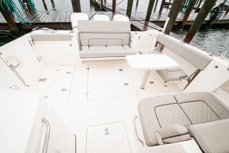 Silver Lining Yacht Photos Pics 2023 Pursuit DC 365 Dual Console boat interior with seating and table, docked by water.