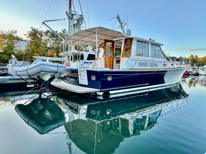 Moonshadow Yacht Photos Pics 2004 Grand Banks 49 Eastbay HX yacht docked, reflecting on calm water.