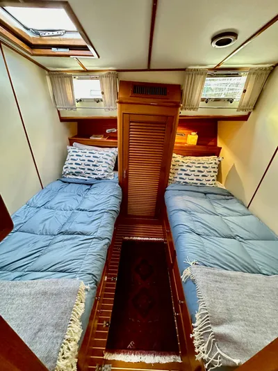 Moonshadow Yacht Photos Pics Cozy twin cabin in 2004 Grand Banks 49 Eastbay HX yacht, featuring blue bedding and wooden accents.