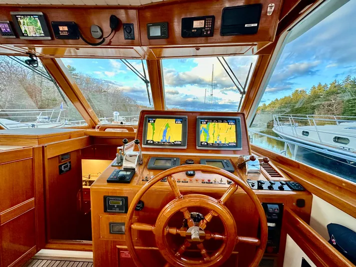 Moonshadow Yacht Photos Pics Helm of 2004 Grand Banks 49 Eastbay HX with navigation screens and wooden steering wheel.
