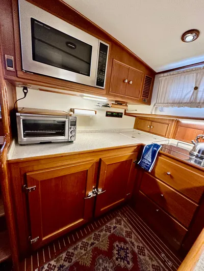 Moonshadow Yacht Photos Pics 2004 Grand Banks 49 Eastbay HX yacht kitchen with microwave, toaster oven, and wooden cabinetry.
