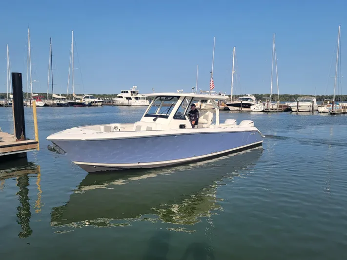 Over Bohr’d Yacht Photos Pics 2023 Pursuit S 328 Sport boat docked in a marina with clear blue skies.
