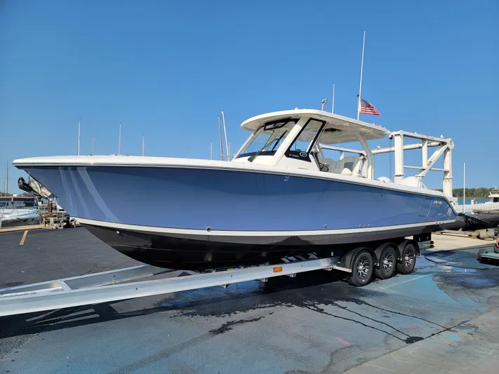Over Bohr’d Yacht Photos Pics 2023 Pursuit S 328 Sport boat on trailer, blue hull, docked at marina.