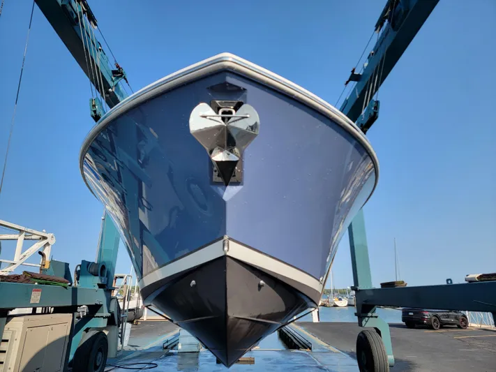 Over Bohr’d Yacht Photos Pics 2023 Pursuit S 328 Sport boat on lift, blue hull, clear sky background.