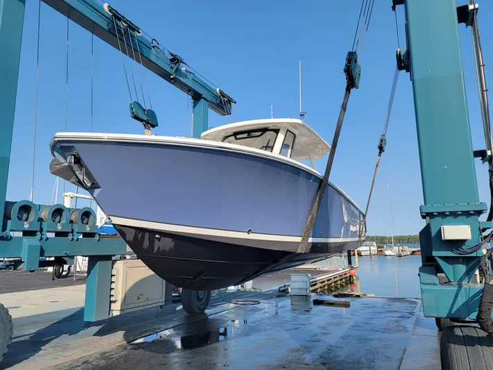 Over Bohr’d Yacht Photos Pics 2023 Pursuit S 328 Sport boat being lifted at a marina.