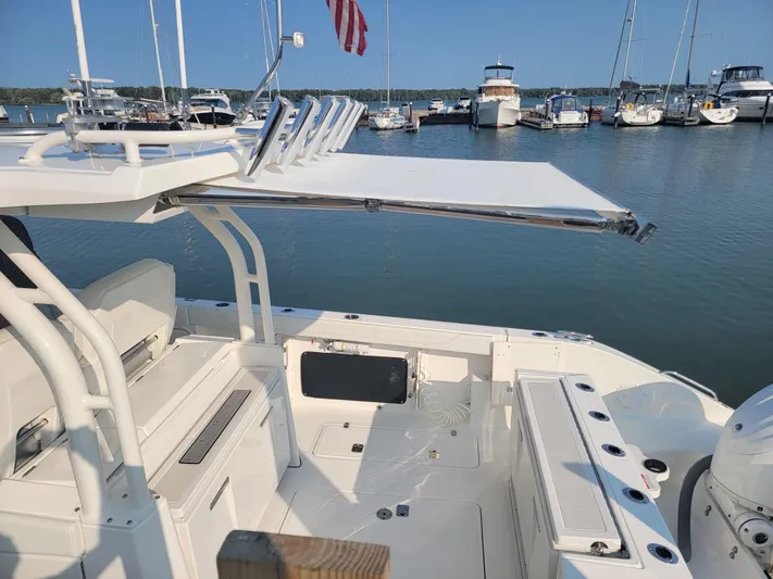 Over Bohr’d Yacht Photos Pics 2023 Pursuit S 328 Sport boat docked at marina with extended sunshade.