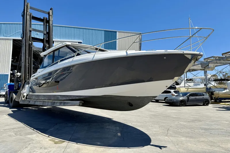  Yacht Photos Pics 2023 Regal 36 XO boat lifted by forklift at marina, clear blue sky background.