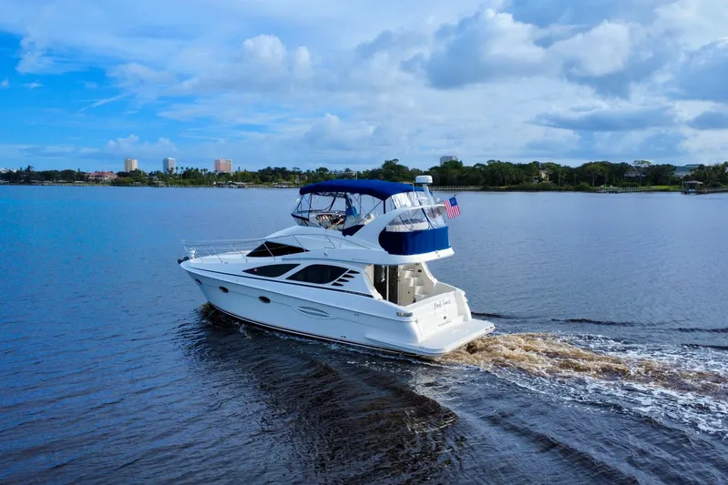  Yacht Photos Pics 2006 Silverton 38 Sport Bridge yacht cruising on a serene lake under a blue sky.