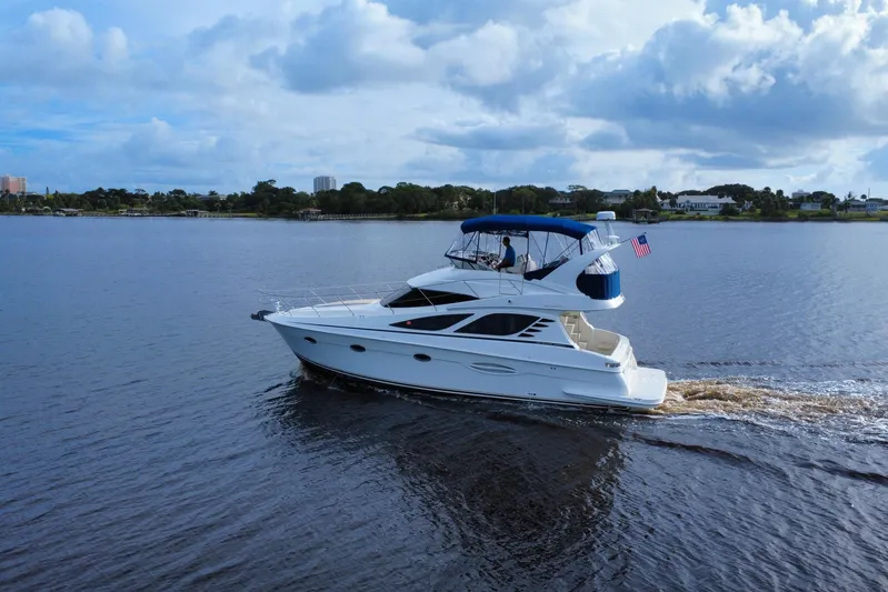  Yacht Photos Pics 2006 Silverton 38 Sport Bridge yacht cruising on a calm lake under a cloudy sky.