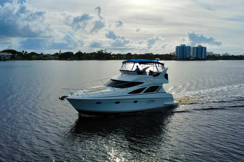  Yacht Photos Pics 2006 Silverton 38 Sport Bridge yacht cruising on a calm waterway under a cloudy sky.