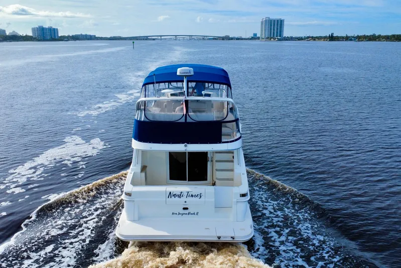  Yacht Photos Pics 2006 Silverton 38 Sport Bridge yacht cruising on a calm river with cityscape background.