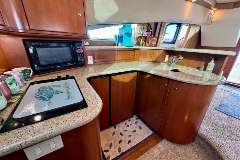  Yacht Photos Pics 2006 Silverton 38 Sport Bridge yacht kitchen with microwave, sink, and wooden cabinetry.