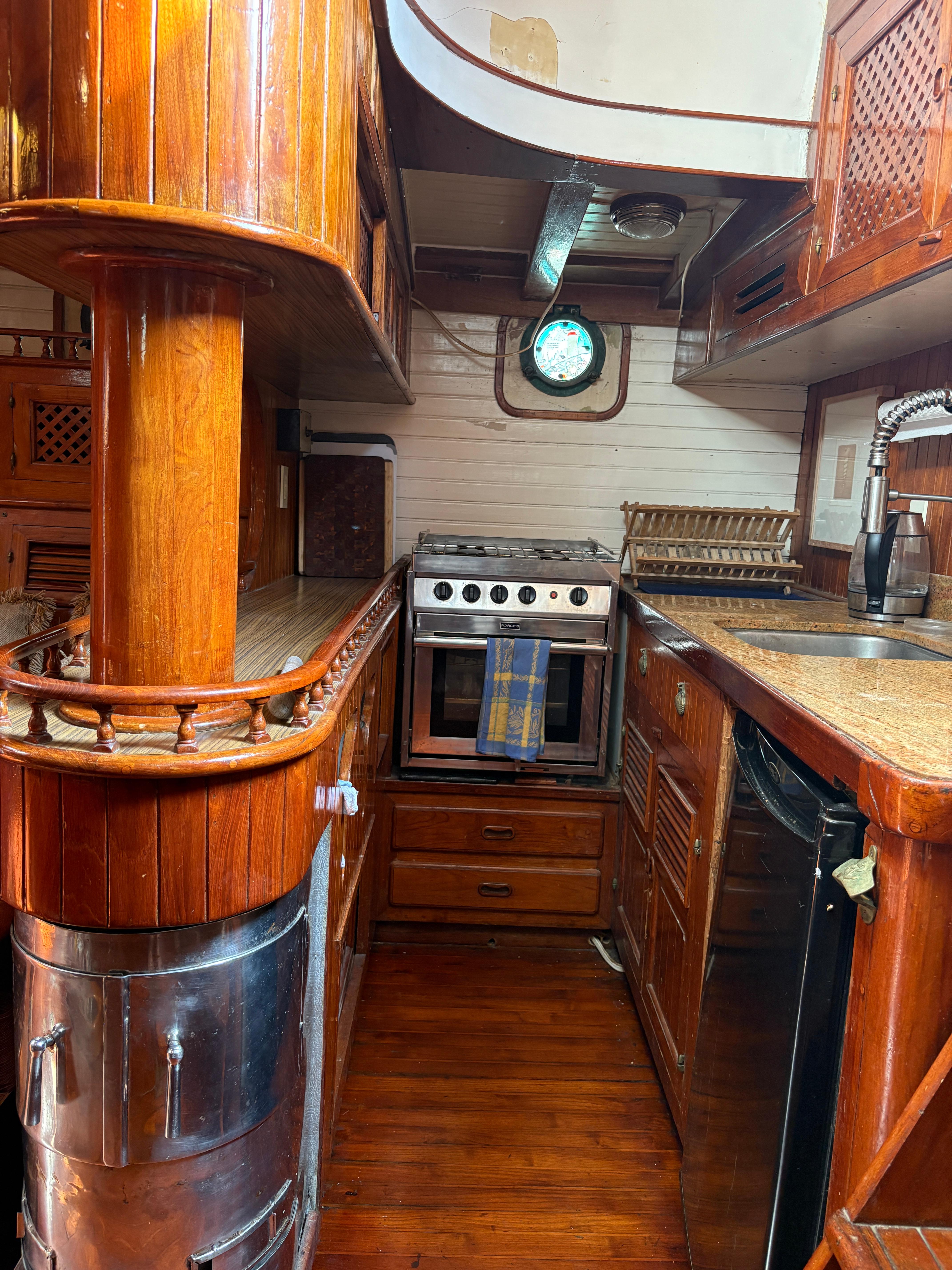 1975 Formosa 51 yacht kitchen with wood finish, stove, and porthole window.