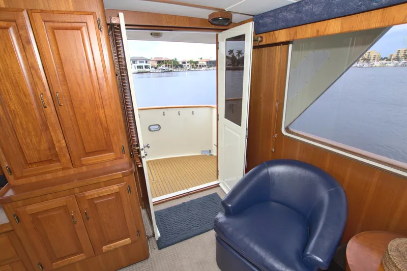 Brown Yacht Photos Pics 1989 Tollycraft 61 Pilothouse Motor Yacht interior with wooden cabinets and blue chair.
