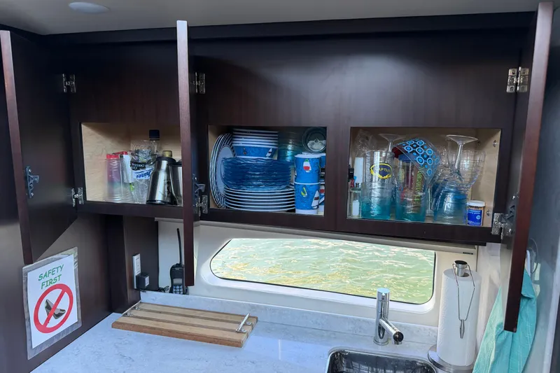 Dancing Queen Yacht Photos Pics Open kitchen cabinet on 2019 Regal 42 Grande Coupe yacht, displaying dishes and glassware.