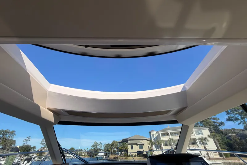 Dancing Queen Yacht Photos Pics 2019 Regal 42 Grande Coupe sunroof view with clear blue sky and waterfront homes.
