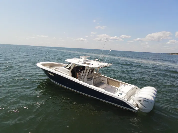 Blue Liner Yacht Photos Pics 2021 Pursuit S 428 Sport boat cruising on open water under a clear sky.