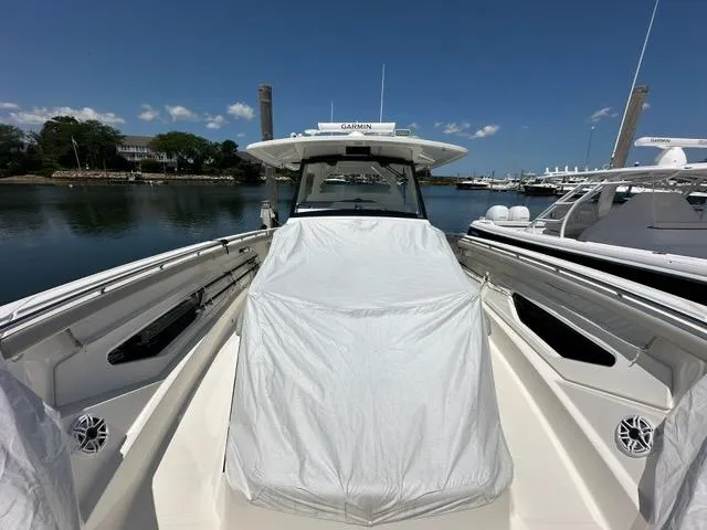 Blue Liner Yacht Photos Pics 2021 Pursuit S 428 Sport boat docked, covered, with clear skies and calm water.