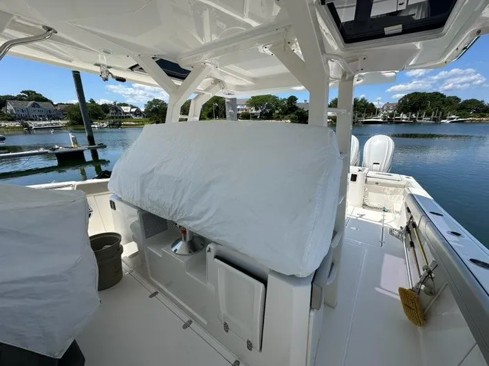 Blue Liner Yacht Photos Pics 2021 Pursuit S 428 Sport boat interior with covered seating, docked by a scenic waterfront.