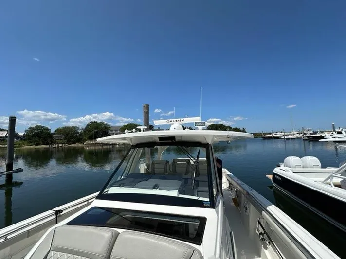 Blue Liner Yacht Photos Pics 2021 Pursuit S 428 Sport boat docked in a serene marina under clear blue skies.