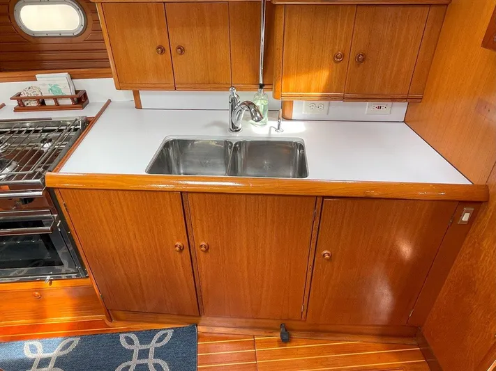 Sea Bear Yacht Photos Pics Galley kitchen in 1998 Jeanneau Sun Odyssey 45.2 sailboat with wooden cabinetry and double sink.