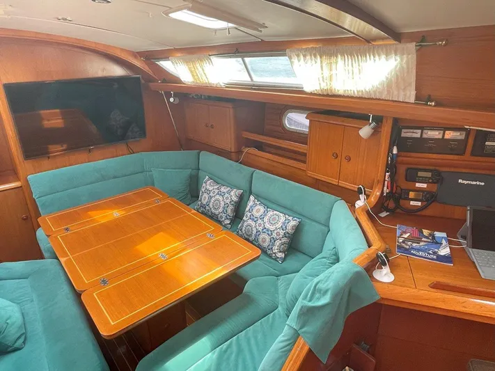 Sea Bear Yacht Photos Pics Interior of 1998 Jeanneau Sun Odyssey 45.2 yacht with teal seating and wooden table.