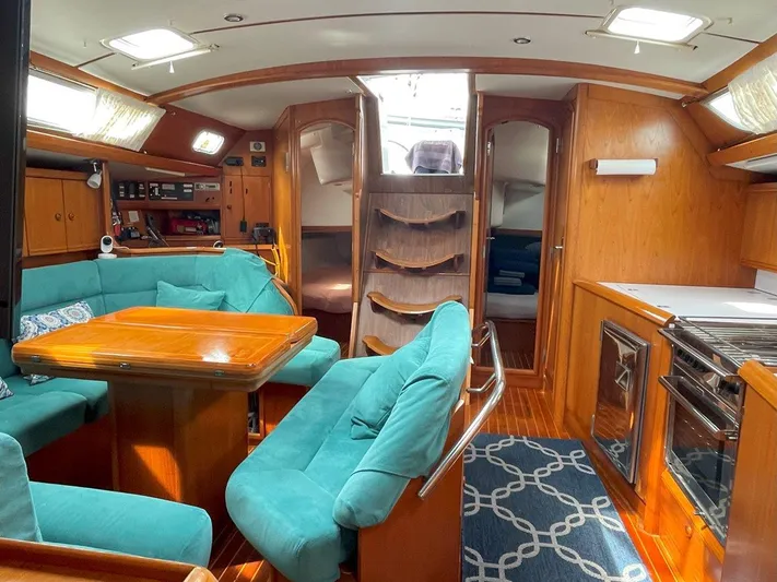 Sea Bear Yacht Photos Pics Interior of 1998 Jeanneau Sun Odyssey 45.2 sailboat with teal seating and wooden finishes.