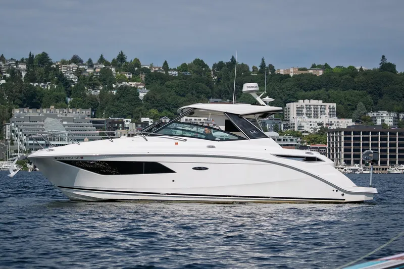  Yacht Photos Pics 2019 Sea Ray Sundancer 320 yacht cruising on a scenic lake with cityscape background.