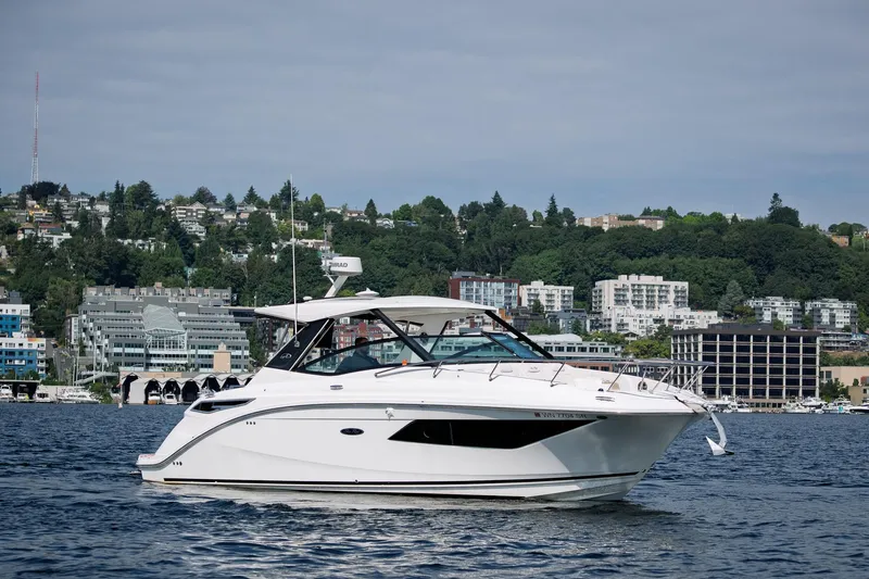  Yacht Photos Pics 2019 Sea Ray Sundancer 320 yacht cruising on a scenic waterfront with cityscape backdrop.