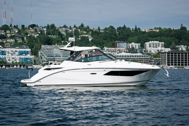  Yacht Photos Pics 2019 Sea Ray Sundancer 320 yacht cruising on a scenic waterfront with city backdrop.
