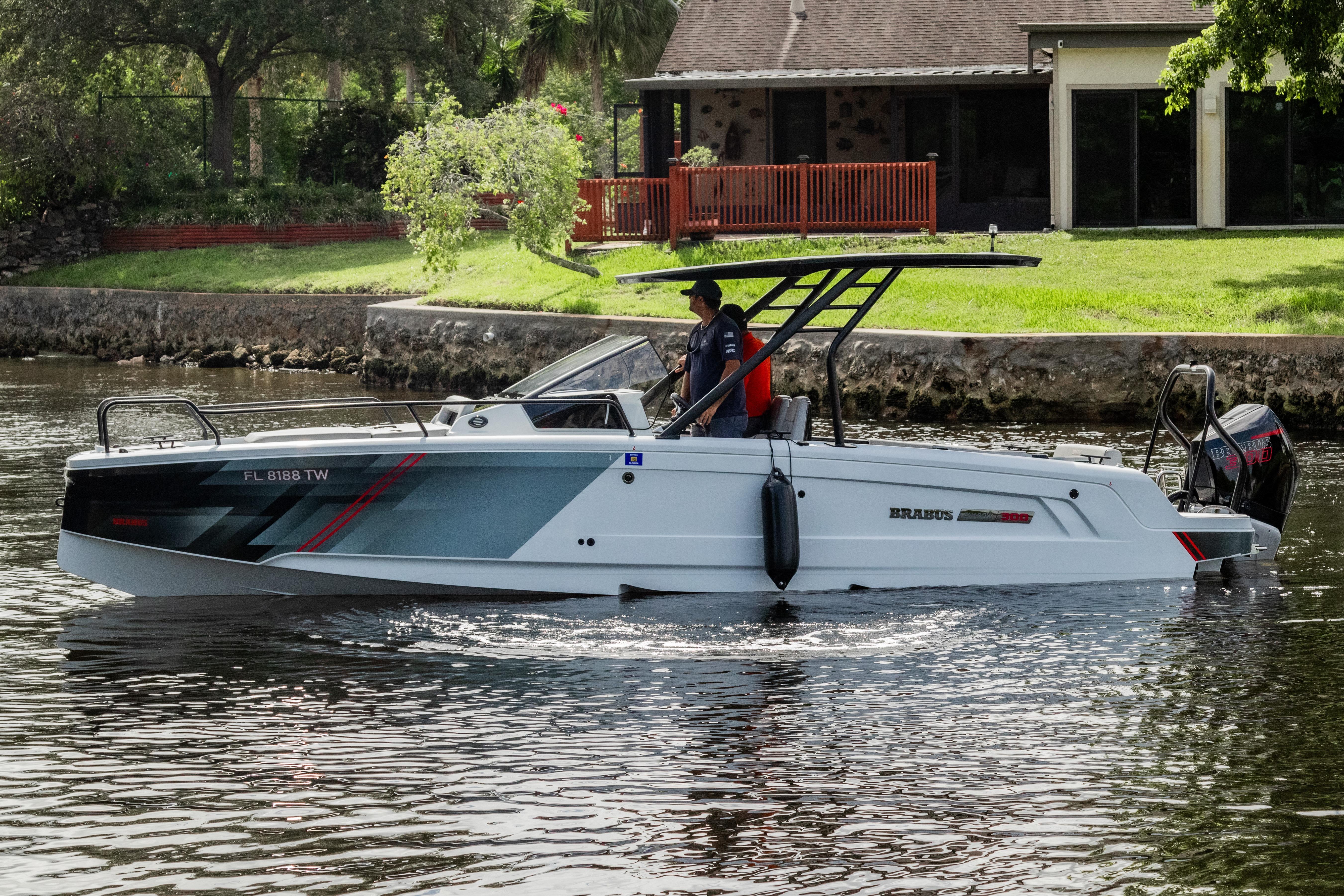 2023 BRABUS Shadow 300 XT boat cruising on a calm river near a house.