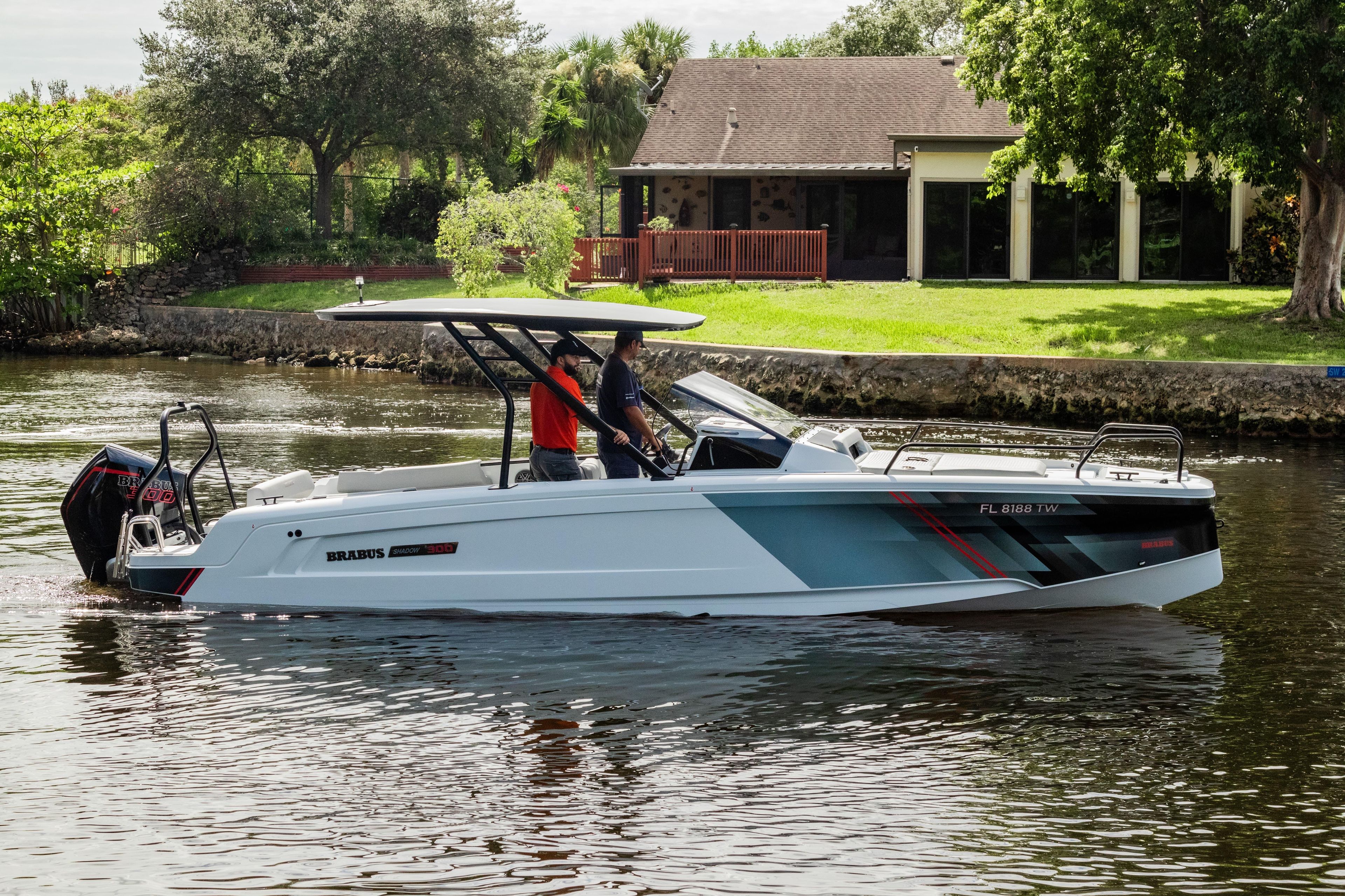 2023 BRABUS Shadow 300 XT boat cruising on a calm river near a house.
