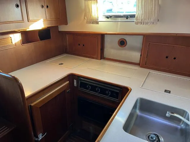 Lio Kai Yacht Photos Pics Interior of 1999 Grand Banks Eastbay 38 yacht kitchen with wooden cabinets and stainless steel sink.