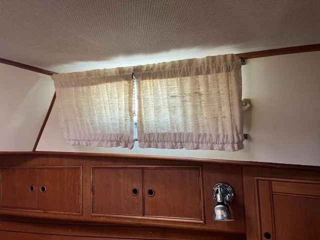 Lio Kai Yacht Photos Pics Interior of 1999 Grand Banks Eastbay 38 with wooden cabinets and curtained window.