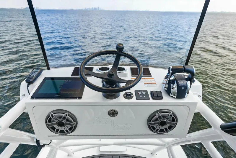 Fish Wish Yacht Photos Pics 2023 SeaVee 450z helm with steering wheel, controls, and navigation system on open water.