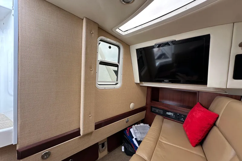  Yacht Photos Pics Interior of 2015 Cobalt 336 boat with TV, beige seating, and red pillow.