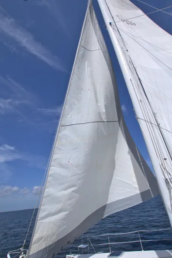 Route 66 Yacht Photos Pics Sails of a 2005 Dolphin 460 Sail Cat against a clear blue sky.