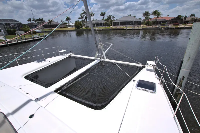 Route 66 Yacht Photos Pics 2005 Dolphin 460 Sail Catamaran docked by waterfront homes under a cloudy sky.