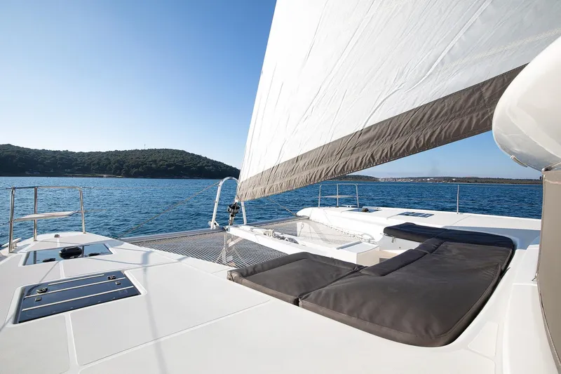 Aliana Yacht Photos Pics 2022 Lagoon 50 catamaran sailing on blue ocean with scenic island backdrop.