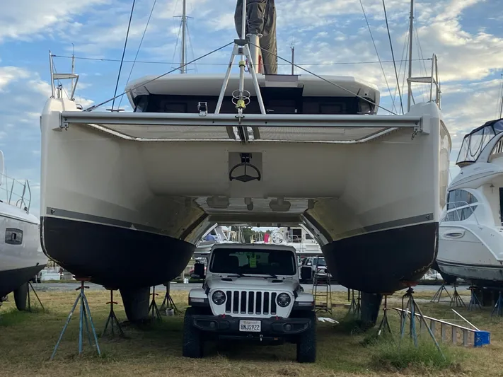 Why Knot Yacht Photos Pics 2020 Robertson Leopard catamaran elevated above a parked Jeep, surrounded by other boats.