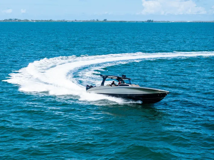  Yacht Photos Pics 2021 MTI V42 speedboat making a sharp turn on clear blue ocean waters.