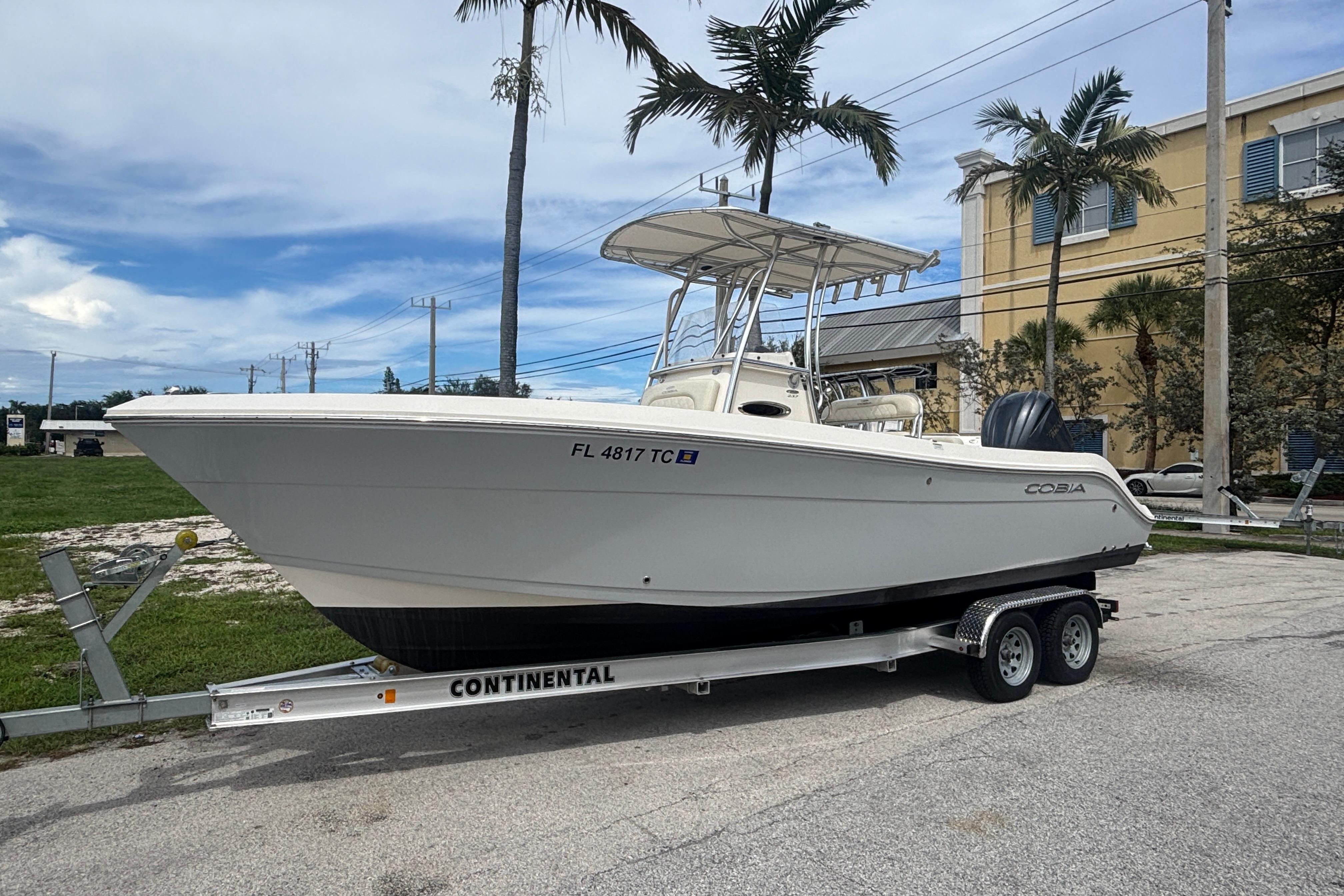 2022 Cobia 237 Center Console boat on trailer, parked outdoors with palm trees.