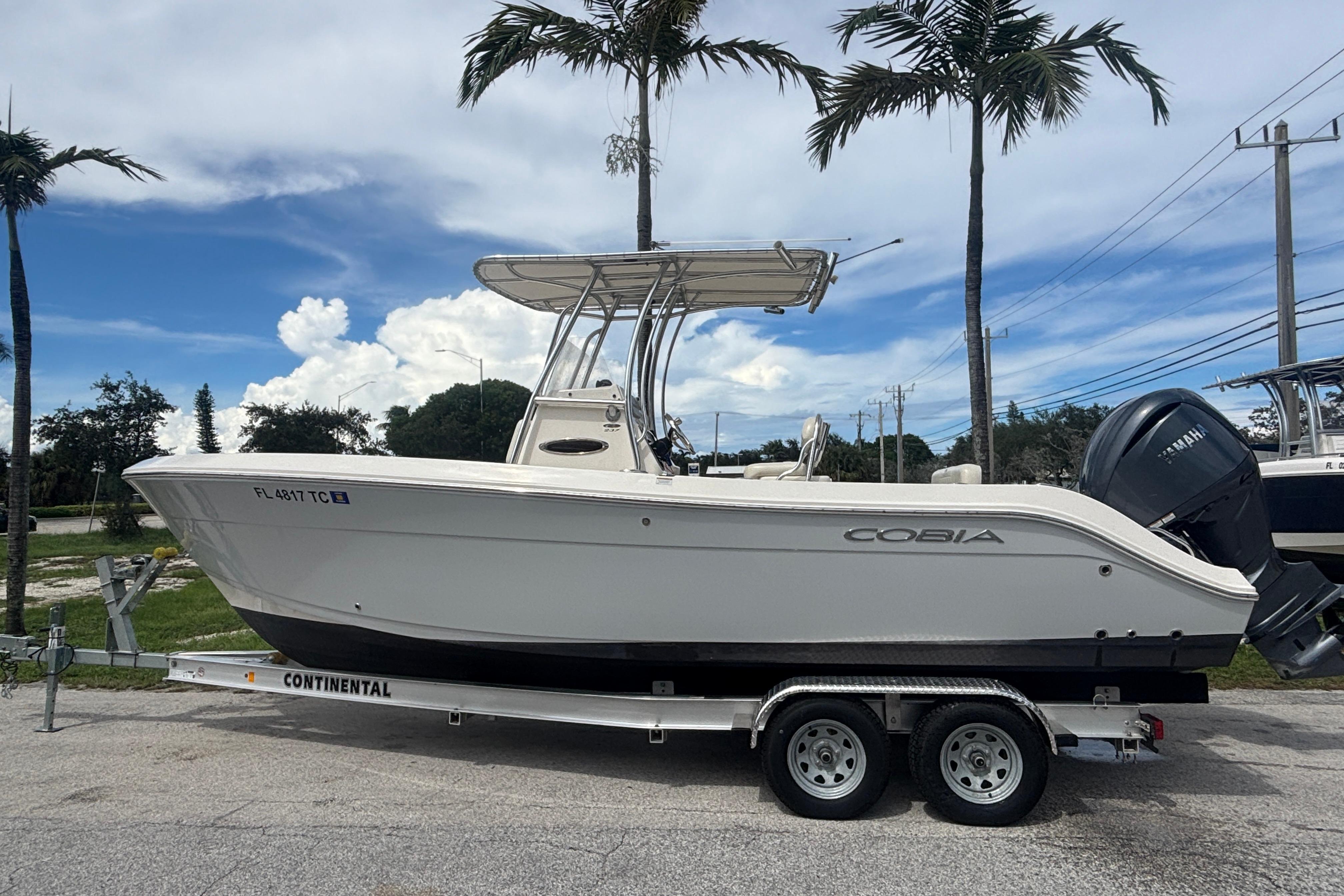 2022 Cobia 237 Center Console boat on trailer, parked under palm trees.