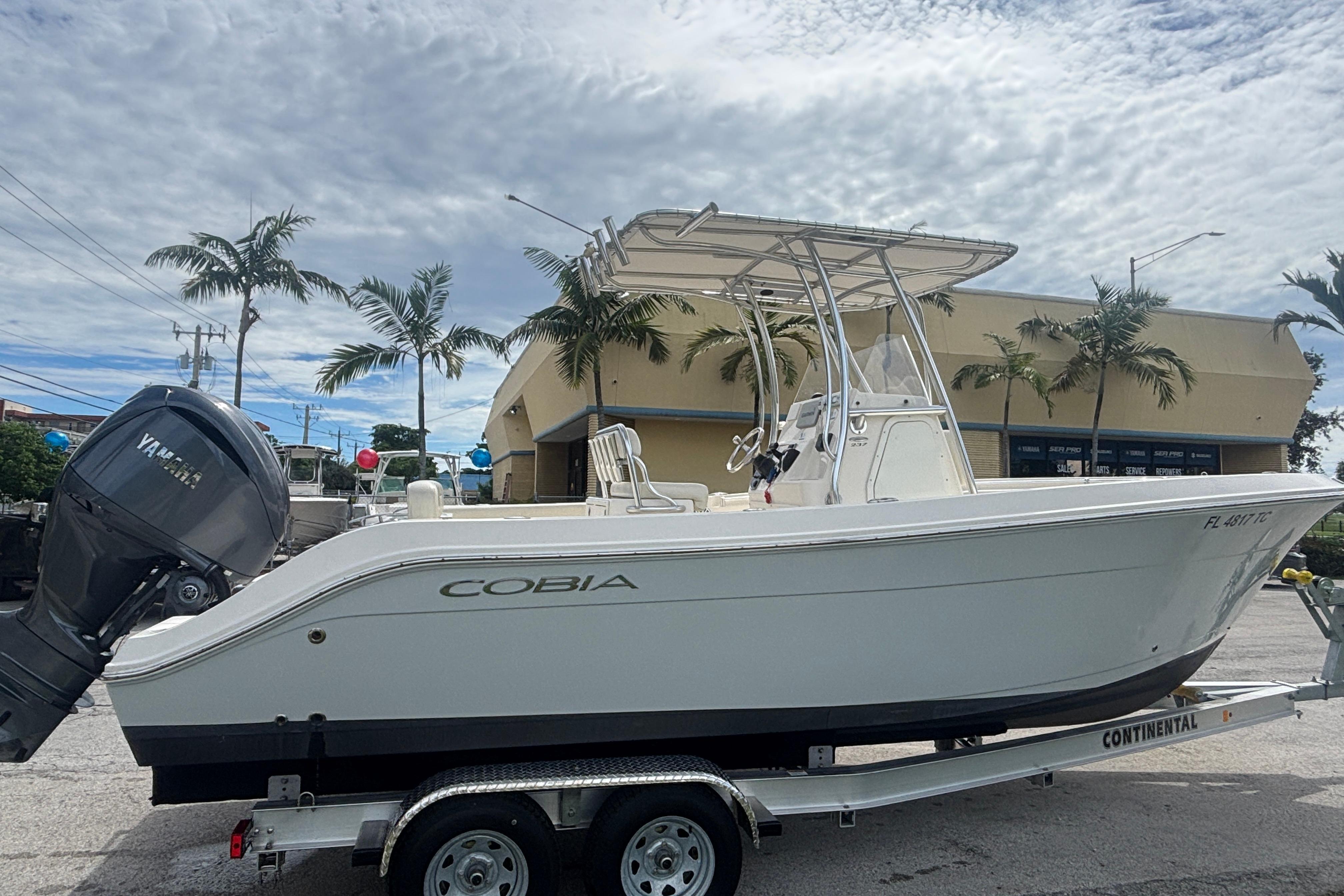 2022 Cobia 237 Center Console boat on trailer, palm trees in background.
