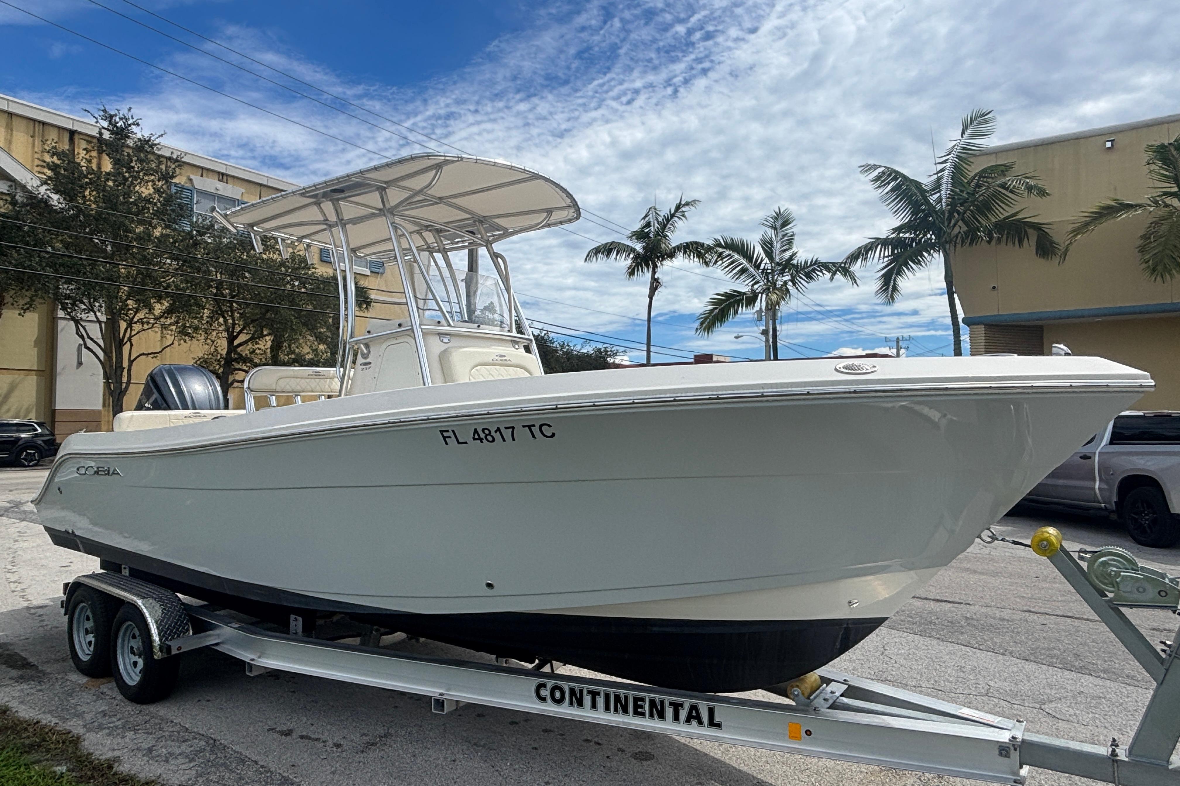 2022 Cobia 237 Center Console boat on trailer, parked outdoors with palm trees.