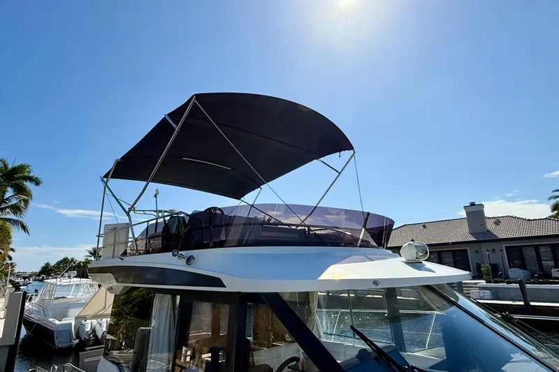  Yacht Photos Pics 2024 Jeanneau NC 1295 Fly yacht with flybridge and canopy, docked under clear blue sky.