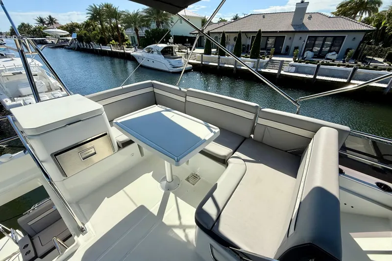  Yacht Photos Pics 2024 Jeanneau NC 1295 Fly yacht flybridge with seating and table, docked by waterfront homes.