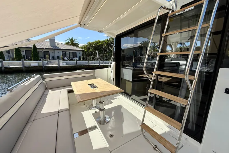  Yacht Photos Pics 2024 Jeanneau NC 1295 Fly yacht deck with seating, table, and ladder.