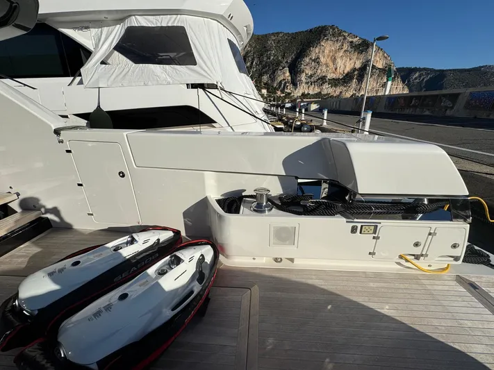  Yacht Photos Pics 2022 Bluegame BGX70 yacht deck with jet skis, docked by scenic cliffs.