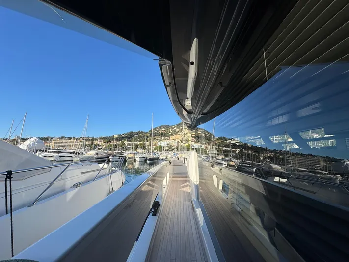  Yacht Photos Pics 2022 Bluegame BGX70 yacht docked in a marina, reflecting clear blue sky and surrounding boats.